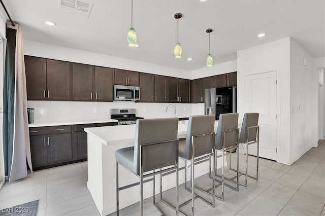 kitchen featuring a breakfast bar, stainless steel appliances, light countertops, and decorative light fixtures