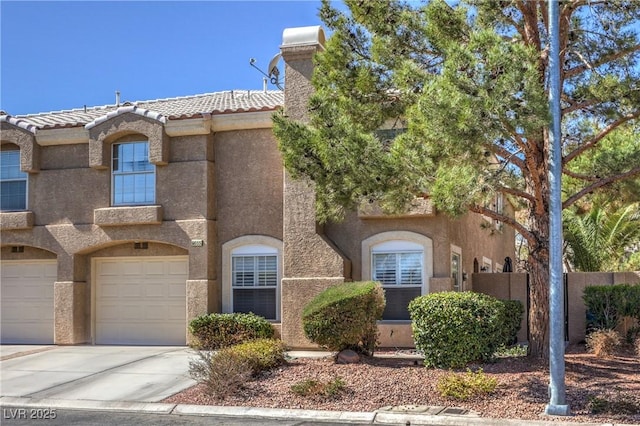 view of front facade with driveway, a tile roof, an attached garage, fence, and stucco siding