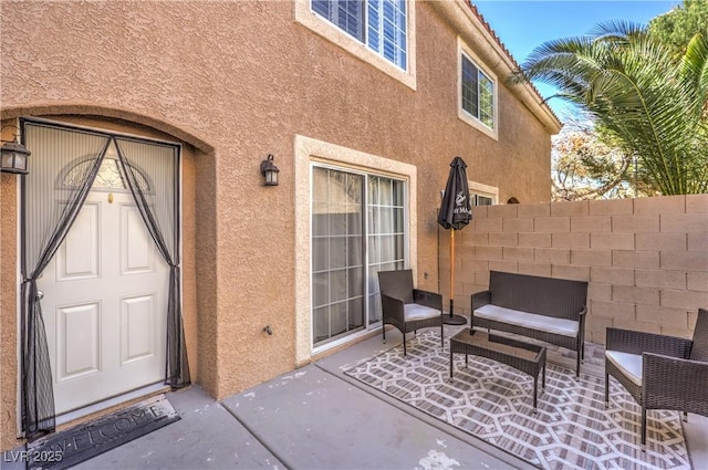 property entrance with fence, a patio, and stucco siding