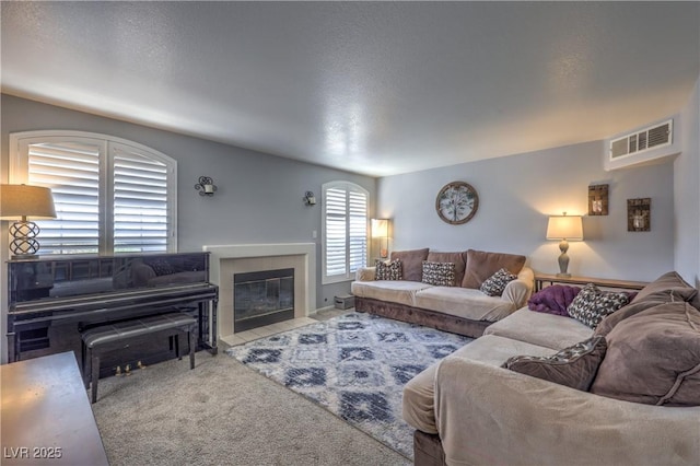 living room with visible vents, carpet flooring, and a tile fireplace