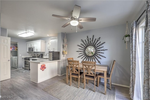 kitchen featuring appliances with stainless steel finishes, white cabinets, a sink, independent washer and dryer, and a peninsula