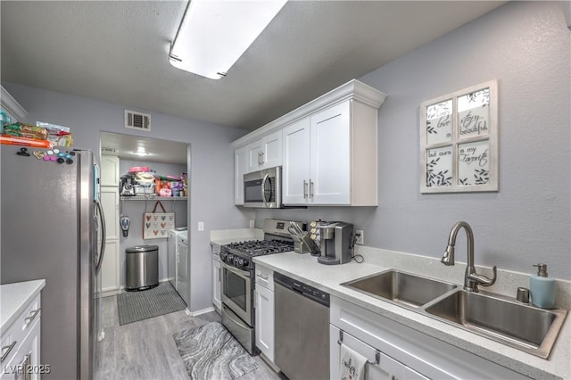 kitchen with light countertops, appliances with stainless steel finishes, a sink, and white cabinetry