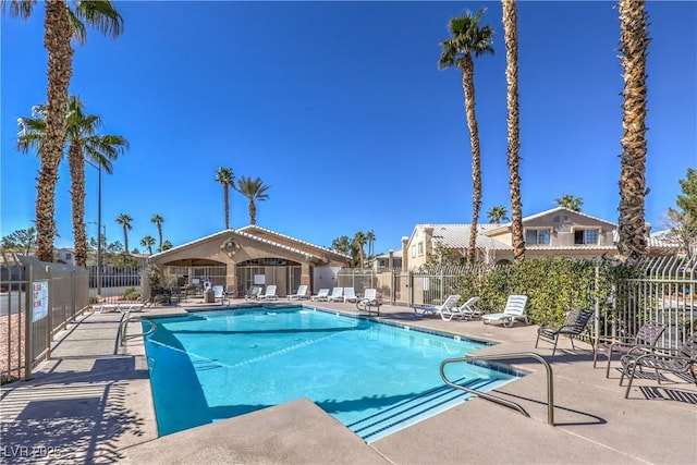 community pool with a patio area and fence