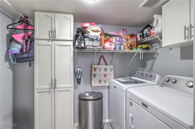 laundry area with cabinet space, visible vents, and washing machine and clothes dryer