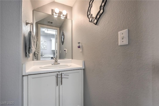 bathroom with a textured wall and vanity