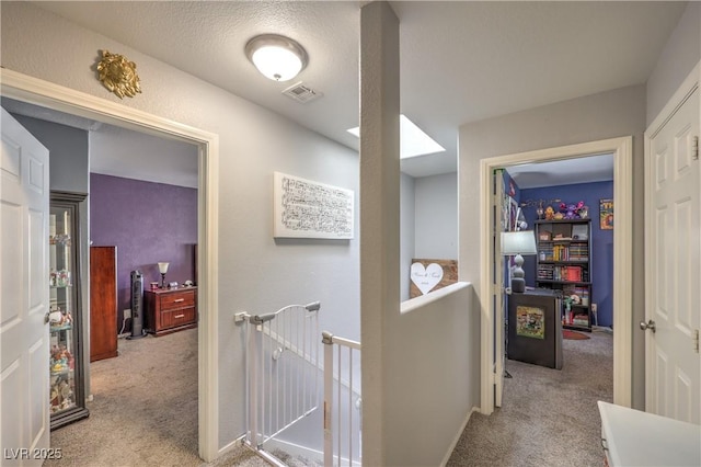 corridor featuring visible vents, light carpet, and an upstairs landing