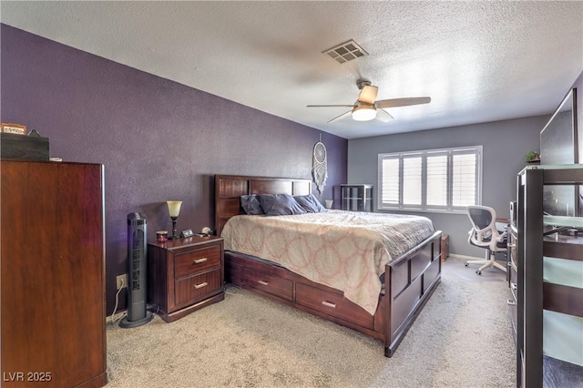 bedroom with light carpet, a textured ceiling, visible vents, and a ceiling fan