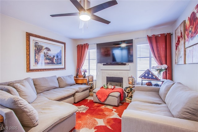 living area with a ceiling fan and a tile fireplace