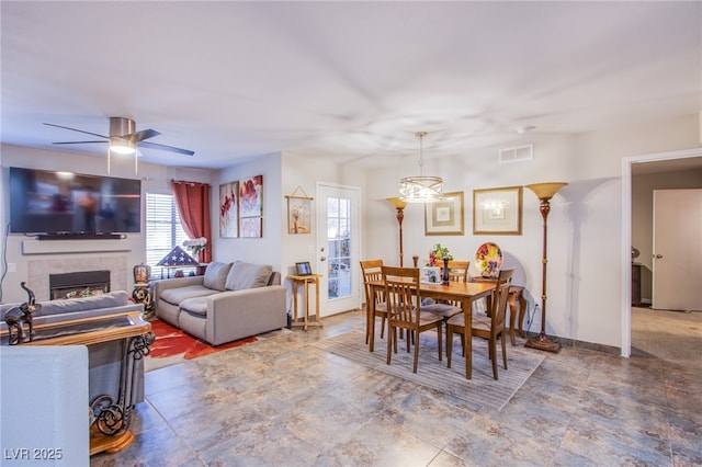 dining space featuring baseboards, a tile fireplace, visible vents, and a ceiling fan