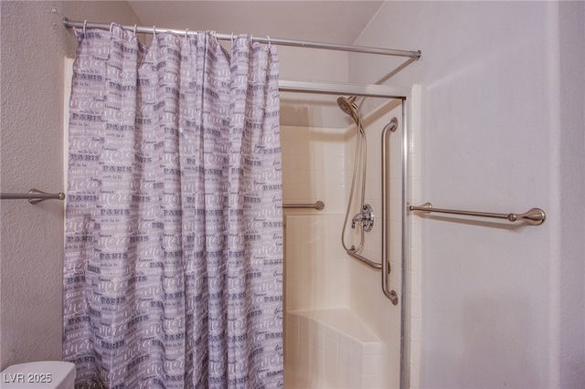 bathroom with toilet, a shower with curtain, and a textured wall