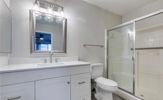 bathroom featuring vanity, a shower stall, and toilet