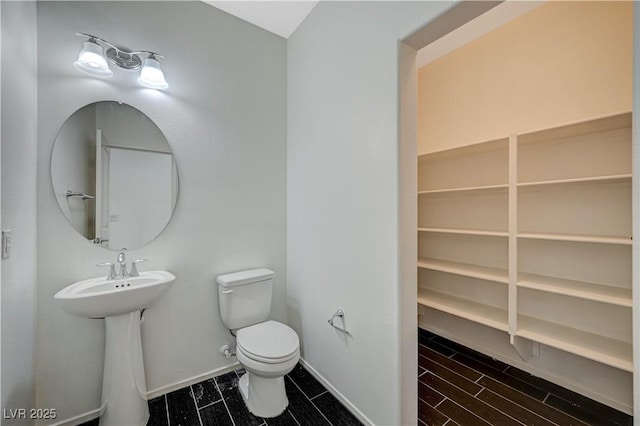 half bath with baseboards, toilet, and wood tiled floor