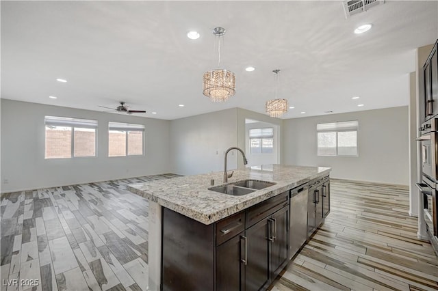 kitchen with a center island with sink, visible vents, open floor plan, and a sink