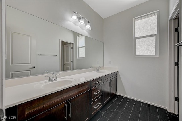 full bath featuring double vanity, baseboards, and a sink