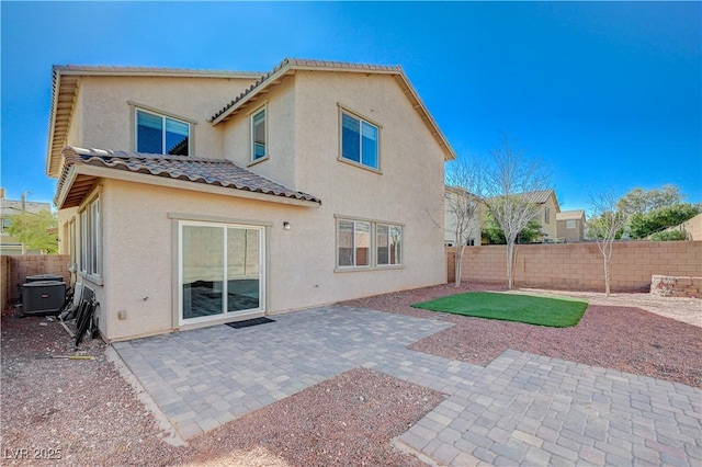 rear view of property featuring a tile roof, central AC unit, stucco siding, a fenced backyard, and a patio area