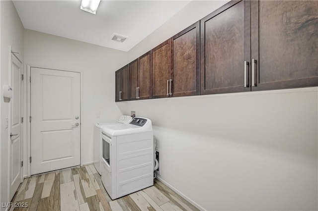 clothes washing area with light wood-style flooring, cabinet space, visible vents, and washing machine and dryer