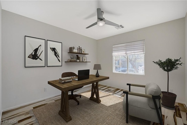 home office featuring wood finished floors, a ceiling fan, visible vents, and baseboards