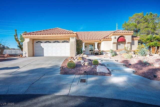 mediterranean / spanish house with a garage, a tiled roof, concrete driveway, and stucco siding