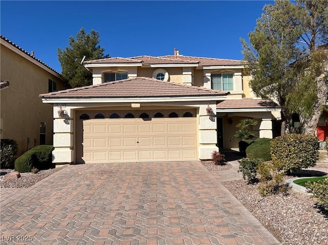 mediterranean / spanish house with decorative driveway, a garage, a tile roof, and stucco siding