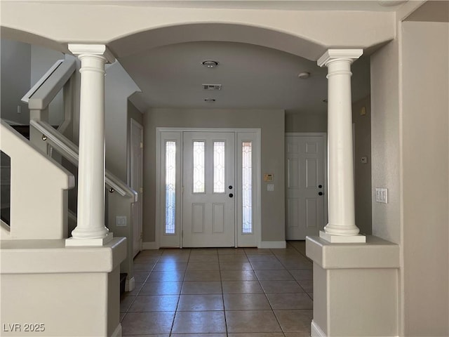 foyer entrance with light tile patterned floors, decorative columns, visible vents, and baseboards