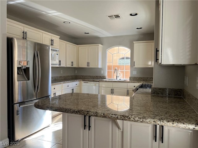 kitchen featuring a peninsula, a sink, visible vents, white cabinetry, and appliances with stainless steel finishes