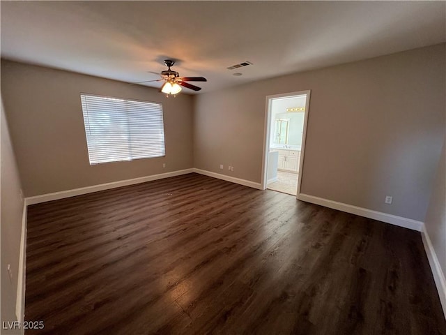 spare room with dark wood-style floors, baseboards, visible vents, and ceiling fan