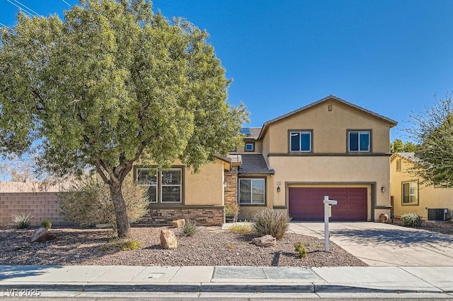 traditional-style home with stucco siding, concrete driveway, fence, a garage, and stone siding