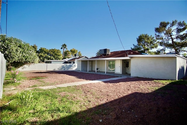 back of property featuring central AC unit, fence, and stucco siding