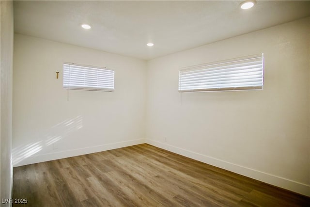 spare room with baseboards, wood finished floors, and recessed lighting