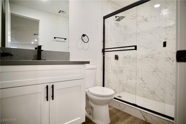 full bathroom with toilet, wood finished floors, vanity, visible vents, and a marble finish shower