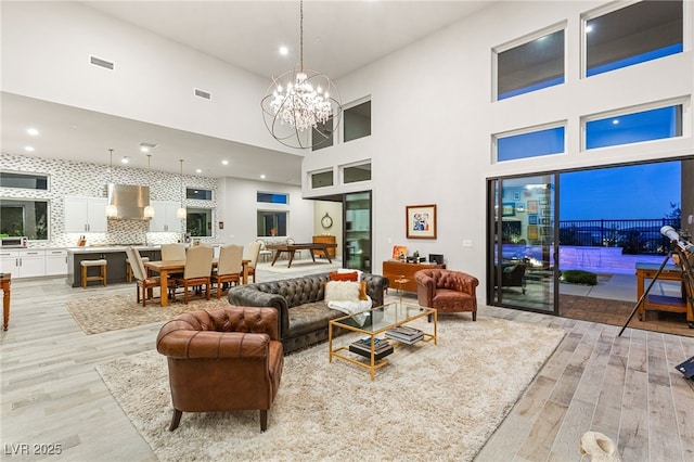 living room featuring a chandelier, light wood finished floors, and visible vents