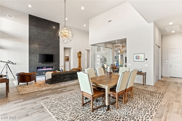 dining space with a large fireplace, recessed lighting, visible vents, and light wood-style floors