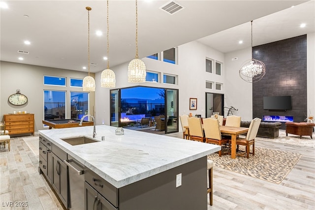 kitchen featuring light wood-style flooring, visible vents, open floor plan, and a sink