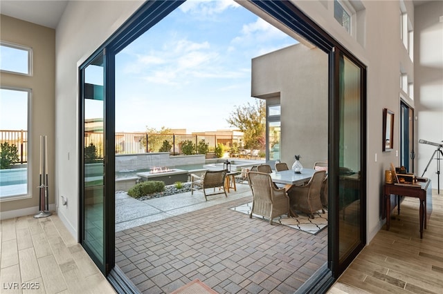 doorway featuring wood finish floors, a towering ceiling, and baseboards