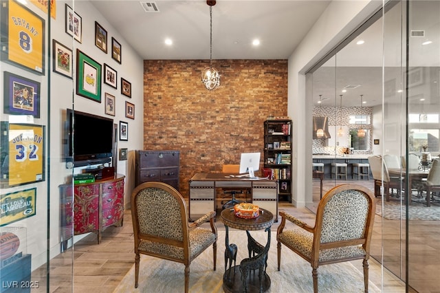 living area featuring visible vents, brick wall, and wood finished floors