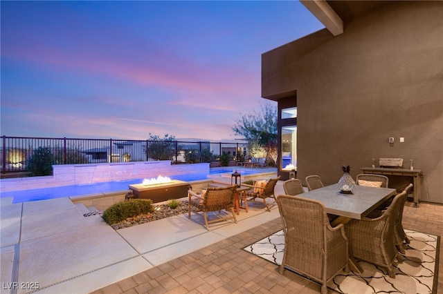 patio terrace at dusk with a fenced in pool, outdoor dining space, and fence