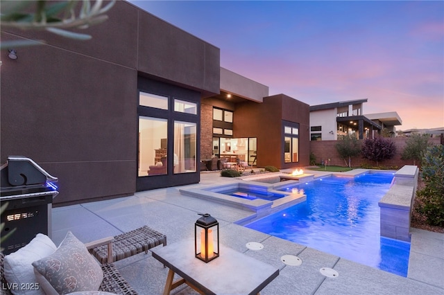 view of pool with a fire pit, a pool with connected hot tub, fence, and a patio