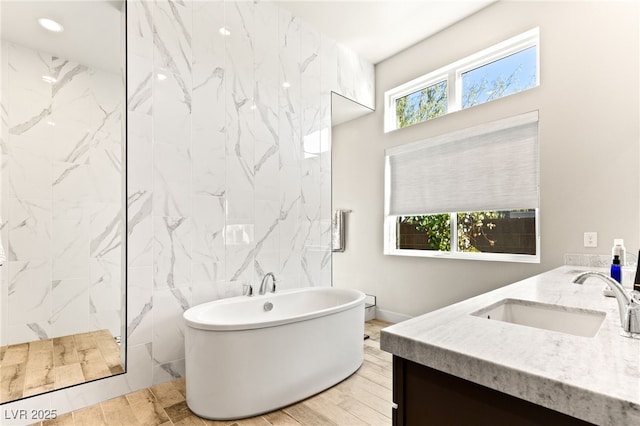 full bath with a marble finish shower, vanity, a freestanding tub, tile walls, and recessed lighting