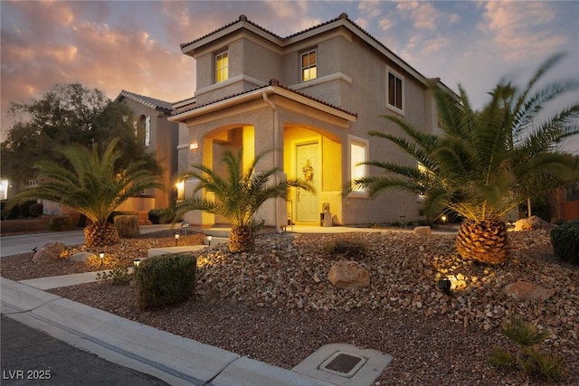 mediterranean / spanish house featuring a tile roof and stucco siding