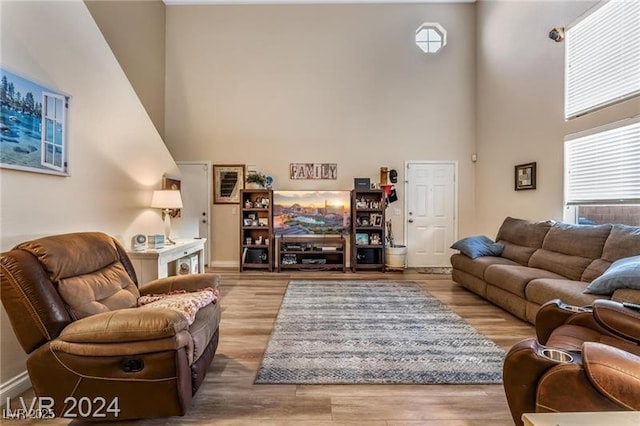 living room with a towering ceiling, wood finished floors, and a wealth of natural light