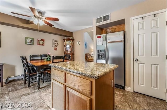 kitchen with visible vents, ceiling fan, light stone counters, a center island, and stainless steel refrigerator with ice dispenser