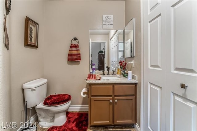 bathroom featuring vanity, toilet, and baseboards