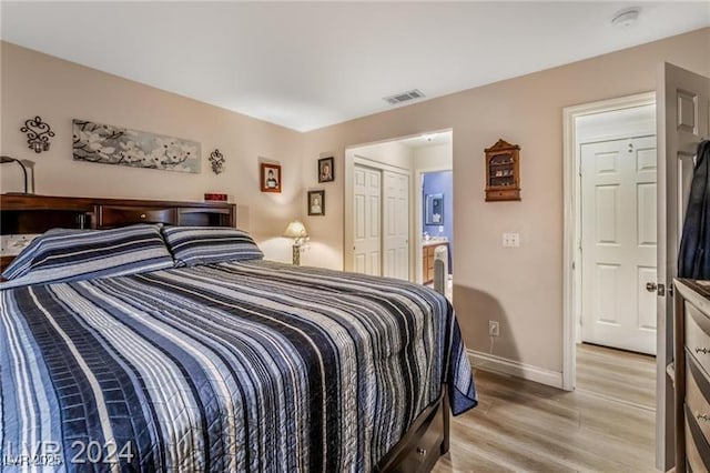 bedroom featuring light wood-type flooring, a closet, visible vents, and baseboards