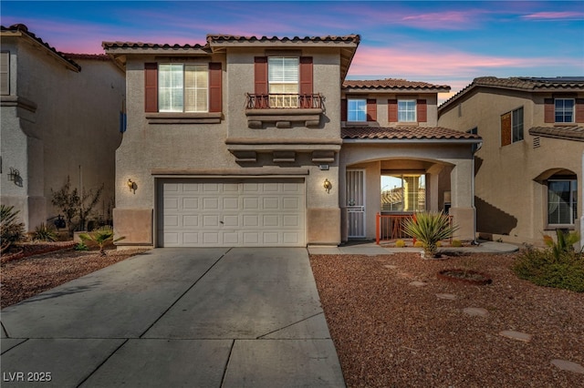 mediterranean / spanish house with a porch, an attached garage, a balcony, driveway, and stucco siding