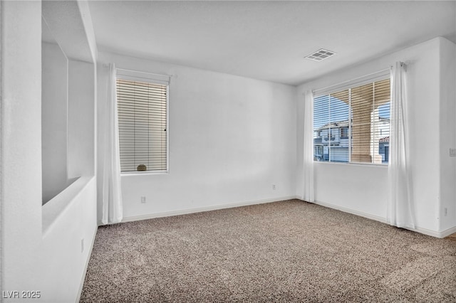 unfurnished room with carpet, visible vents, and baseboards