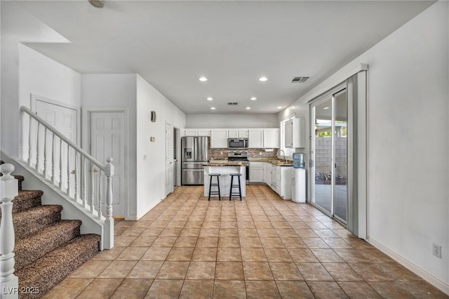 kitchen with visible vents, decorative backsplash, white cabinets, appliances with stainless steel finishes, and a sink