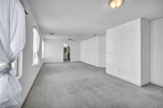 spare room featuring a ceiling fan, light colored carpet, visible vents, and baseboards