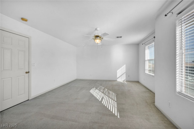 empty room with baseboards, visible vents, ceiling fan, and carpet flooring