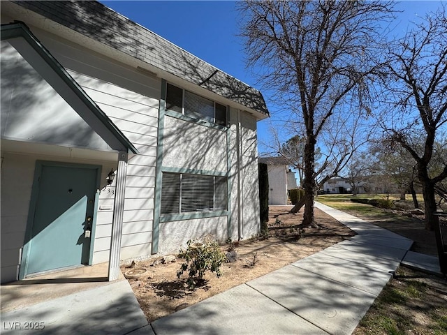 view of side of property with roof with shingles and mansard roof