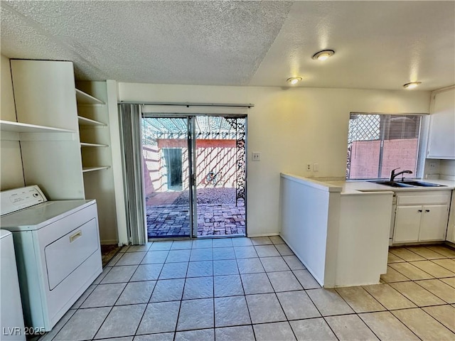 kitchen with light countertops, white cabinets, a sink, light tile patterned flooring, and separate washer and dryer